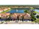 Aerial view of a townhome community surrounding a lake with a fountain and a nearby swimming pool area at 3456 Parkridge Cir # 33-105, Sarasota, FL 34243