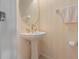 Bathroom featuring a pedestal sink with gold fixtures, an oval mirror, and light peach walls at 3456 Parkridge Cir # 33-105, Sarasota, FL 34243
