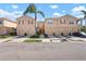 A row of tan townhomes with well-manicured lawns and driveways, each featuring garages and a central palm tree at 3456 Parkridge Cir # 33-105, Sarasota, FL 34243