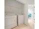 Bright laundry area with washer, dryer, overhead shelving, and entry to bedroom at 3456 Parkridge Cir # 33-105, Sarasota, FL 34243