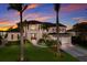 Elegant two-story home with lush landscaping, paved driveway, and a porte-cochere with palm trees at sunset at 348 W Royal Flamingo Dr, Sarasota, FL 34236
