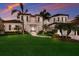 A luxurious two-story home featuring a well-manicured lawn, mature palms, and elegant architectural details at sunset at 348 W Royal Flamingo Dr, Sarasota, FL 34236