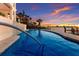 Stunning waterfront pool with vibrant blue water and a picturesque sunset backdrop; outdoor luxury at 348 W Royal Flamingo Dr, Sarasota, FL 34236