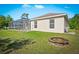Exterior shot of the back of the property with a fire pit, large screened in patio, and a spacious green yard at 3528 Monday Ter, North Port, FL 34286
