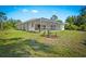 Exterior shot of the back of the property with a large screened in patio, newly landscaped area, and a spacious green yard at 3528 Monday Ter, North Port, FL 34286
