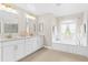 Bright bathroom featuring a soaking tub, white cabinets, and double sinks with plenty of lighting at 3528 Monday Ter, North Port, FL 34286
