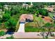 Aerial view of single-story home with long driveway, attached two-car garage, and screened pool in a lush green neighborhood at 3528 Monday Ter, North Port, FL 34286