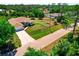 Aerial view of single-story home with long driveway, attached two-car garage, and side lot in a lush green neighborhood at 3528 Monday Ter, North Port, FL 34286