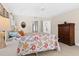 Bright main bedroom with a floral quilt, tile floors, and a vintage wood dresser at 3528 Monday Ter, North Port, FL 34286