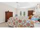 Bright main bedroom with a floral quilt, tile floors, two vintage wood dressers, and access to the outside at 3528 Monday Ter, North Port, FL 34286