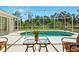 Screened-in pool area featuring a quaint table, chairs, and beautiful outdoor scenery beyond the screened enclosure at 3528 Monday Ter, North Port, FL 34286