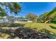 Wide shot of the backyard with green lawn, privacy fence, mature trees, and play area at 436 Parkview Dr, Sarasota, FL 34243