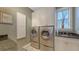 Bright laundry room features a side-by-side washer and dryer, granite countertops, and ample storage cabinets at 4941 Commonwealth Dr, Sarasota, FL 34242