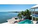 Stunning aerial view of waterfront property featuring a pool, dock, and lush landscaping with tropical palms at 511 Bayview Dr, Holmes Beach, FL 34217