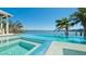 Inviting infinity pool and hot tub with stunning water views and lush tropical landscaping at 511 Bayview Dr, Holmes Beach, FL 34217