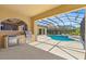 Outdoor kitchen and screened-in pool area with a sparkling pool and spacious patio at 5270 White Ibis Dr, North Port, FL 34287