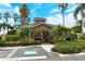 Community clubhouse entrance with stone accents, lush landscaping, and a convenient parking area at 5450 Soapstone Pl # 9-103, Sarasota, FL 34233