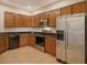 A kitchen showcases brown cabinets, stainless steel appliances, and modern tile flooring at 5450 Soapstone Pl # 9-103, Sarasota, FL 34233