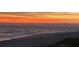 Beach landscape at dusk with a colorful sunset reflecting on the ocean and casting shadows on the sand at 619 Bayview Dr, Longboat Key, FL 34228