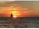 A sailboat on the horizon against a vibrant sunset, casting a warm glow over the tranquil ocean waters at 619 Bayview Dr, Longboat Key, FL 34228