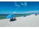 Relaxing beach scene with blue umbrella and chairs on the white sand, facing the clear blue water at 6503 Fairway Gardens Dr # 20-201, Bradenton, FL 34203