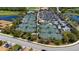 This aerial view shows well maintained tennis courts near a lake, pool and clubhouse at 6708 Grand Estuary Trl # 104, Bradenton, FL 34212