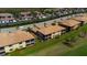 An aerial view of townhomes with tiled roofs and private screened patios backing to a lush green lawn at 6708 Grand Estuary Trl # 104, Bradenton, FL 34212