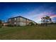 A serene backyard view with lush green grass and screened in patio on a two-story building near a pond at twilight at 6708 Grand Estuary Trl # 104, Bradenton, FL 34212