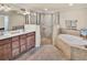 Bathroom featuring a soaking tub, a glass-enclosed shower, and a double vanity with dark wood cabinets at 6708 Grand Estuary Trl # 104, Bradenton, FL 34212
