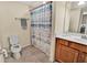 This bathroom features a shower with an ocean-themed curtain, toilet and single sink with wooden cabinets at 6708 Grand Estuary Trl # 104, Bradenton, FL 34212