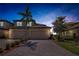 Charming two-story home featuring a paved driveway, two-car garage, and meticulously landscaped front yard at twilight at 6708 Grand Estuary Trl # 104, Bradenton, FL 34212