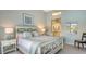 A beautifully decorated bedroom with a gorgeous white wood headboard and a view into the ensuite bathroom at 7742 Whitebridge Gln, University Park, FL 34201