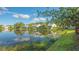 Scenic water view of homes with screened lanais, reflecting in a tranquil lake under a partly cloudy sky at 7742 Whitebridge Gln, University Park, FL 34201