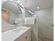 Bathroom boasts modern round mirror, vanity, and frameless glass shower with stone tile floor and tiled walls at 100 Sands Point Rd # 225, Longboat Key, FL 34228