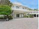 Inviting condo building exterior featuring lush landscaping, covered parking, and accessible entrance at 100 Sands Point Rd # 225, Longboat Key, FL 34228