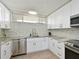 Well-lit kitchen with white cabinets, stainless steel appliances, and granite countertops at 100 Sands Point Rd # 225, Longboat Key, FL 34228