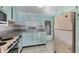 Charming kitchen featuring pastel blue cabinetry, neutral backsplash, and traditional appliances at 1224 41St Avenue E Dr, Ellenton, FL 34222