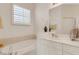 Bright bathroom featuring a soaking tub, single sink vanity, and white cabinetry at 1311 Triano Cir # 1311, Venice, FL 34292