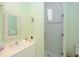 Well-lit bathroom with white cabinets, decorative mirror and tiled walk-in shower at 2050 Benjamin Franklin Dr # A1001, Sarasota, FL 34236