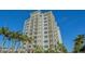 Beautiful condo building with white facade, multiple balconies, and tropical landscaping against a clear blue sky at 2050 Benjamin Franklin Dr # A1001, Sarasota, FL 34236