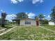 Exterior of a home with neutral paint, carport, small yard, and a bright red front door at 21114 Gladis Ave, Port Charlotte, FL 33952