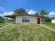Exterior of a home with neutral paint, carport, small yard, and a bright red front door at 21114 Gladis Ave, Port Charlotte, FL 33952