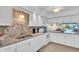 Bright kitchen features white cabinets and updated appliances with a tile backsplash at 235 Rotonda W Blvd # C102, Rotonda West, FL 33947