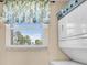 Cozy laundry area with stacked washer/dryer and a window with charming seashell curtains at 235 Rotonda W Blvd # C102, Rotonda West, FL 33947