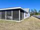 Rear view of the home featuring a screened-in patio and spacious backyard with sunny skies above at 3608 67Th Street Ct W, Bradenton, FL 34209