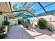 Outdoor patio area featuring brick pavers, a screened enclosure, dining set with umbrella, and greenery at 4091 Center Pointe Pl # 40A, Sarasota, FL 34233