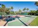 Community shuffleboard and tennis courts surrounded by mature trees, creating a recreational space at 5013 Village Gardens Dr # 34, Sarasota, FL 34234