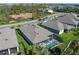 An aerial view shows the home with pool, landscaping, and nearby street and pond at 5621 Badini Way, Palmetto, FL 34221