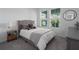 Cozy bedroom with gray tufted headboard, and bright windows showcasing lush greenery at 5621 Badini Way, Palmetto, FL 34221