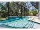 A refreshing screened pool with waterfall feature offers a serene retreat with a view of lush greenery at 5621 Badini Way, Palmetto, FL 34221
